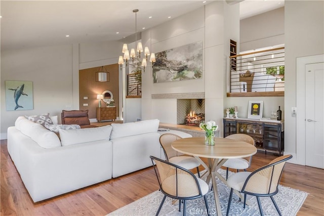 dining area with a high ceiling, a chandelier, and light hardwood / wood-style flooring