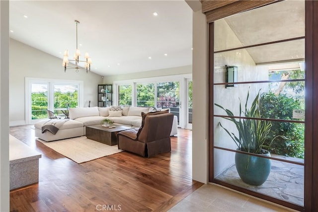 living room featuring a wealth of natural light, lofted ceiling, a chandelier, and wood-type flooring