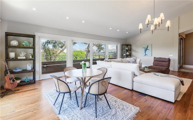 dining room with light hardwood / wood-style floors, lofted ceiling, and a chandelier