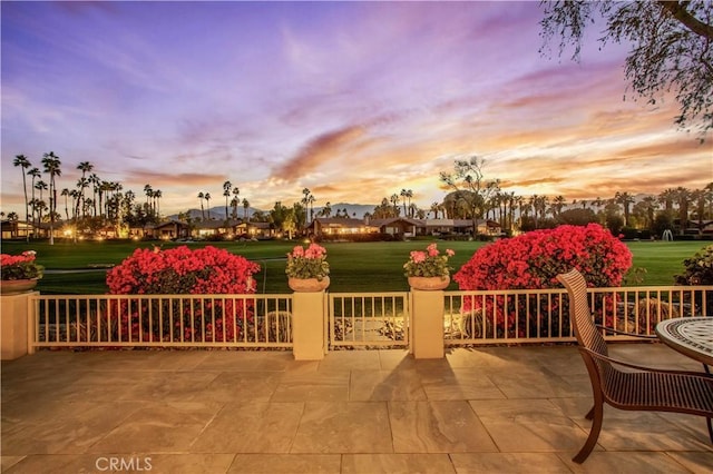 patio terrace at dusk featuring a lawn