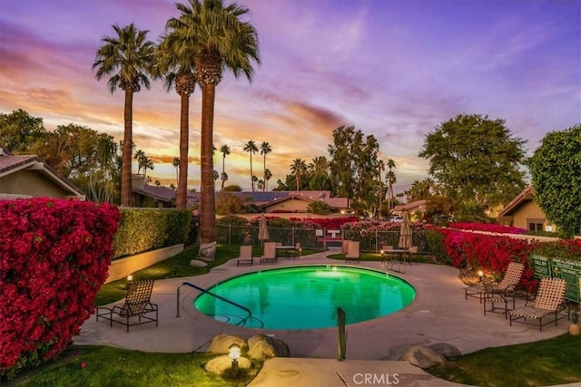 pool at dusk featuring a patio