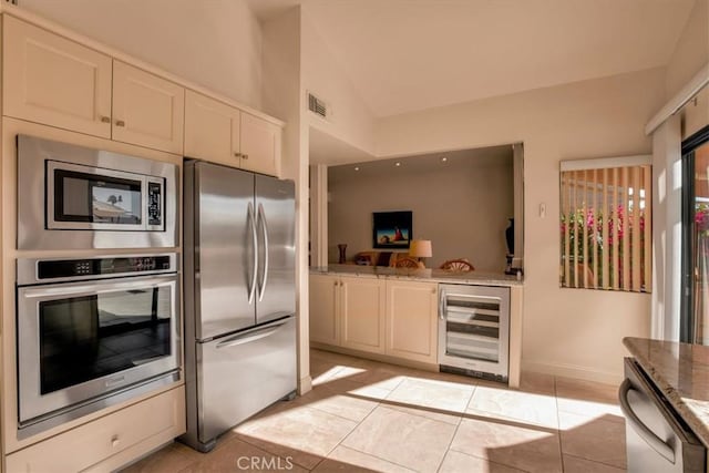 kitchen featuring stone counters, lofted ceiling, wine cooler, light tile patterned floors, and stainless steel appliances