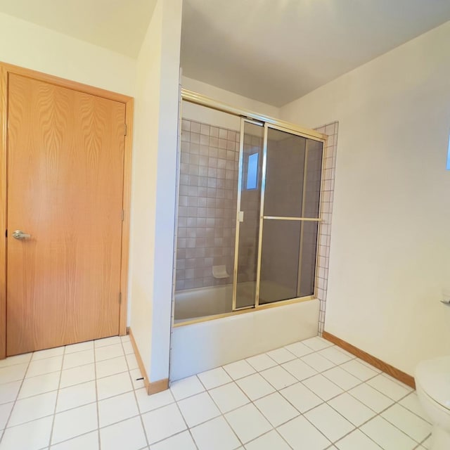 bathroom featuring combined bath / shower with glass door, toilet, and tile patterned flooring