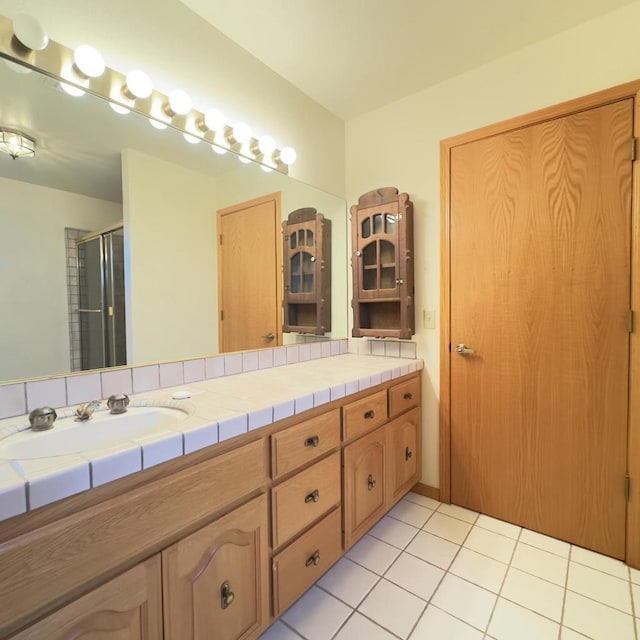 bathroom with a shower with shower door, tile patterned floors, and vanity