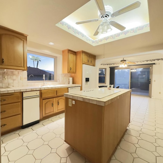 kitchen with decorative backsplash, white fridge with ice dispenser, a raised ceiling, and tile countertops