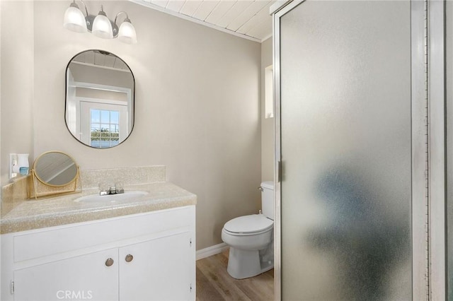 bathroom featuring baseboards, toilet, wood finished floors, an enclosed shower, and vanity