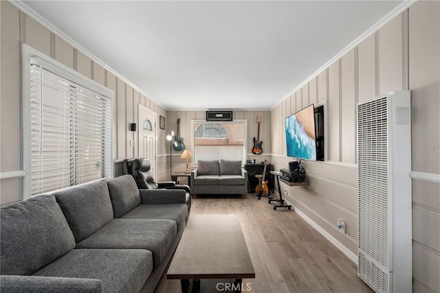 living area featuring a decorative wall, wood finished floors, a heating unit, and ornamental molding