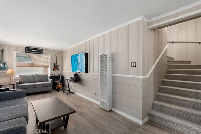 living room with stairway, a decorative wall, wood finished floors, and ornamental molding