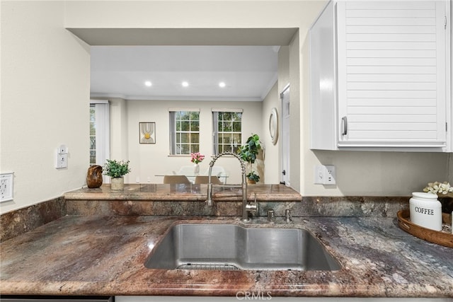 kitchen with sink, crown molding, and dark stone counters