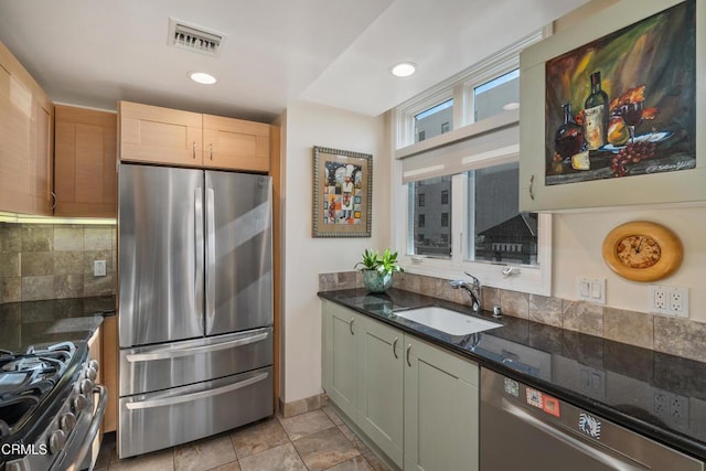 kitchen with sink, appliances with stainless steel finishes, decorative backsplash, dark stone counters, and light brown cabinets