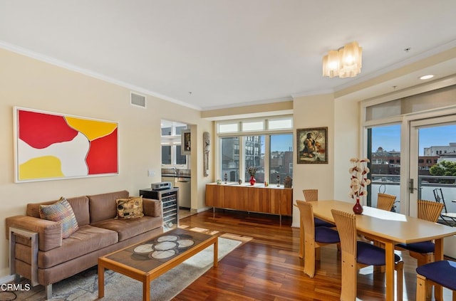 living room with dark hardwood / wood-style flooring, a notable chandelier, plenty of natural light, and ornamental molding