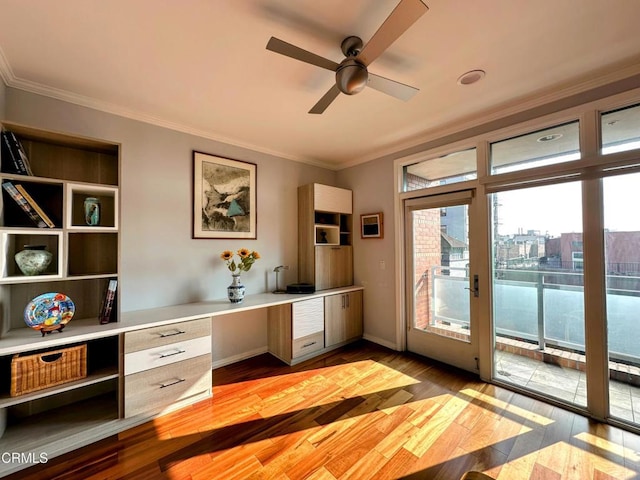 unfurnished office featuring light hardwood / wood-style flooring, crown molding, built in desk, and ceiling fan