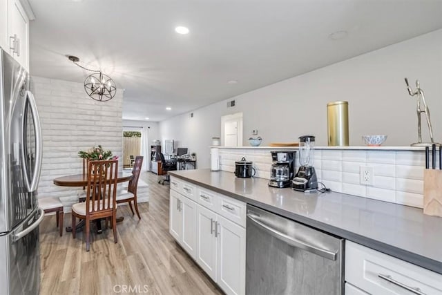 kitchen with white cabinetry, stainless steel appliances, a notable chandelier, pendant lighting, and light hardwood / wood-style flooring