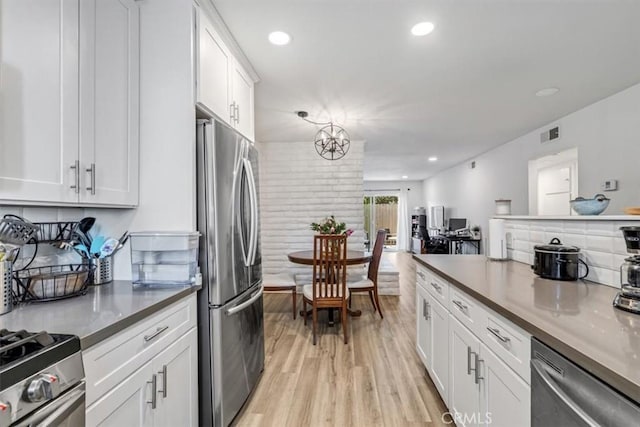 kitchen with stainless steel appliances, light hardwood / wood-style flooring, white cabinetry, and a chandelier