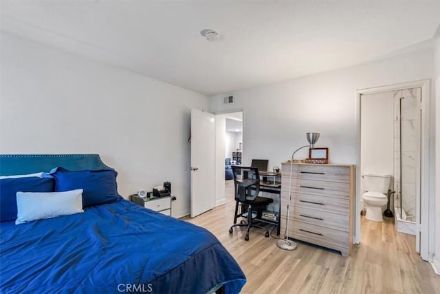 bedroom with ensuite bath and light wood-type flooring