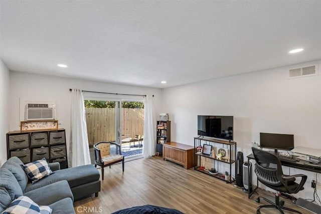 living room with a wall mounted AC and light hardwood / wood-style floors