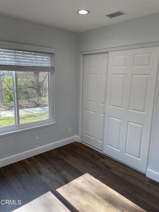 unfurnished bedroom with a closet and dark hardwood / wood-style floors