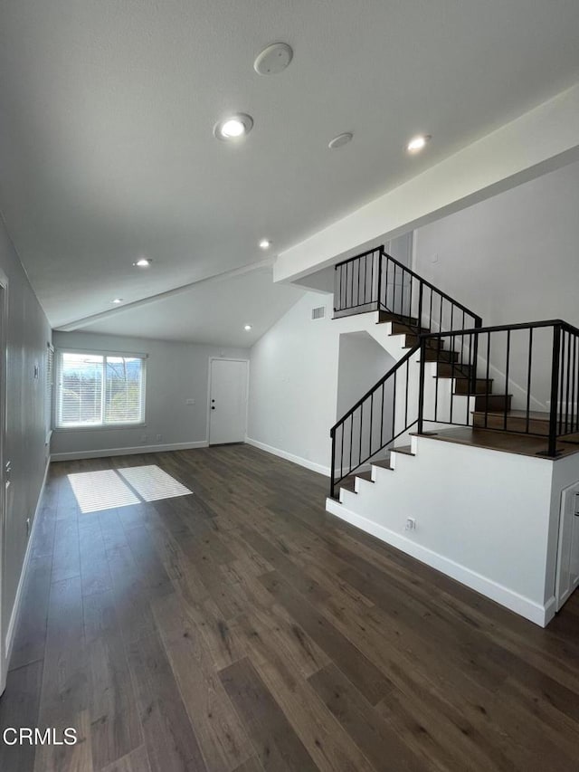 unfurnished living room featuring vaulted ceiling and dark hardwood / wood-style flooring