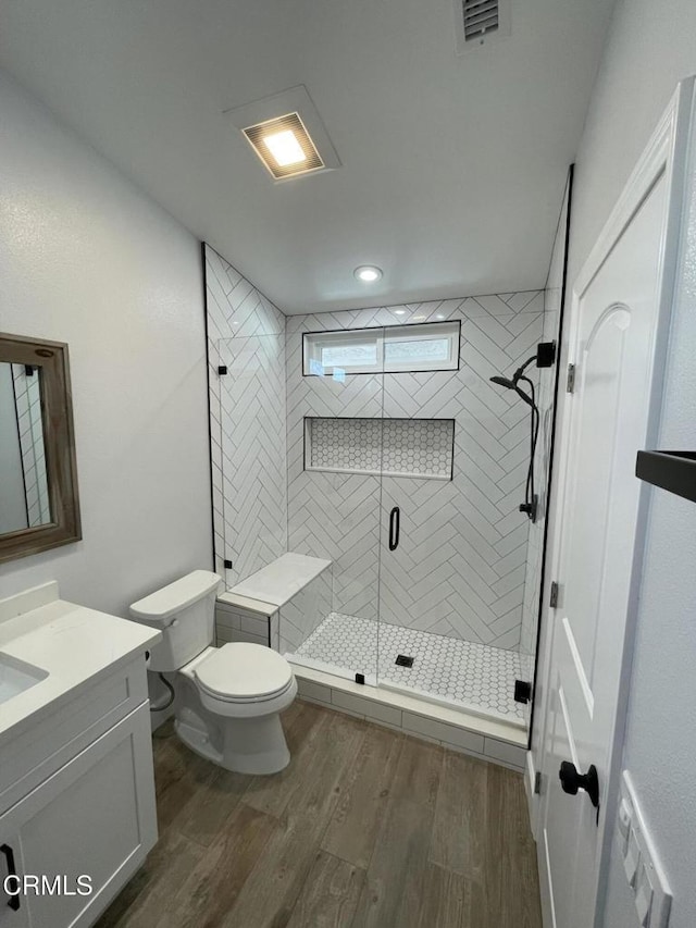 bathroom featuring toilet, a shower with shower door, hardwood / wood-style flooring, and vanity