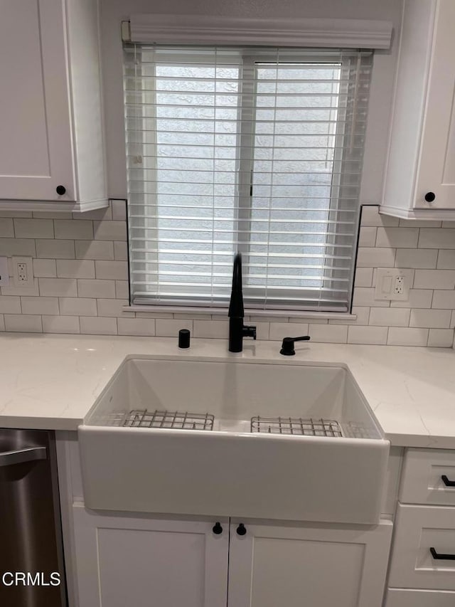 kitchen with backsplash, dishwasher, sink, light stone countertops, and white cabinets