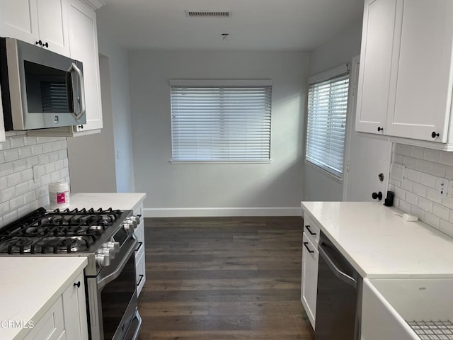 kitchen with backsplash, white cabinets, dark hardwood / wood-style floors, and stainless steel appliances