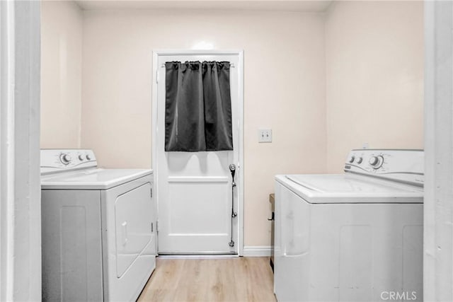 clothes washing area featuring washer and clothes dryer and light wood-type flooring