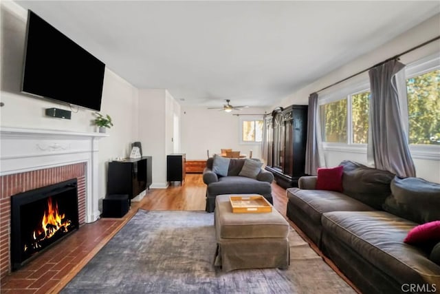 living room featuring hardwood / wood-style flooring, a brick fireplace, and ceiling fan