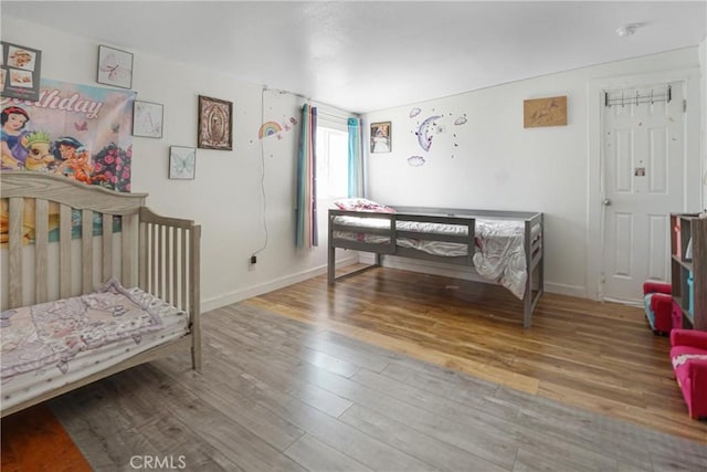 bedroom with hardwood / wood-style floors and a crib