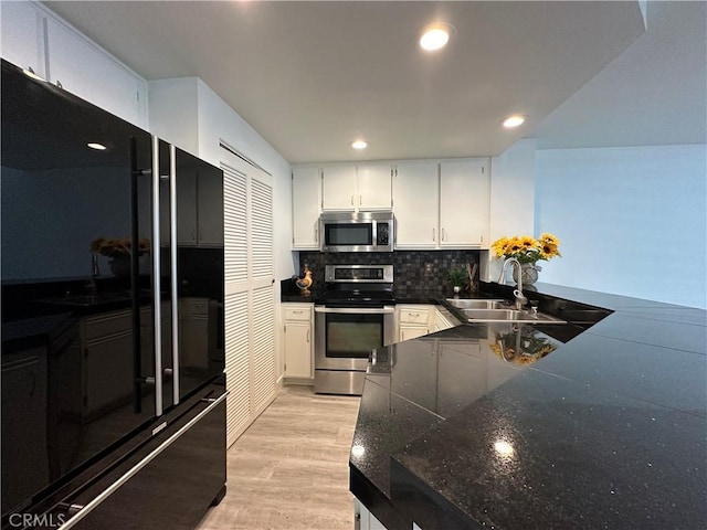 kitchen with decorative backsplash, sink, white cabinetry, and stainless steel appliances