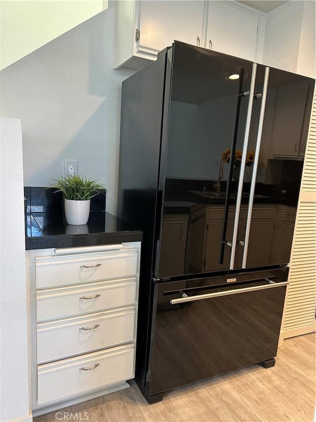 kitchen featuring black refrigerator, white cabinetry, and light hardwood / wood-style floors