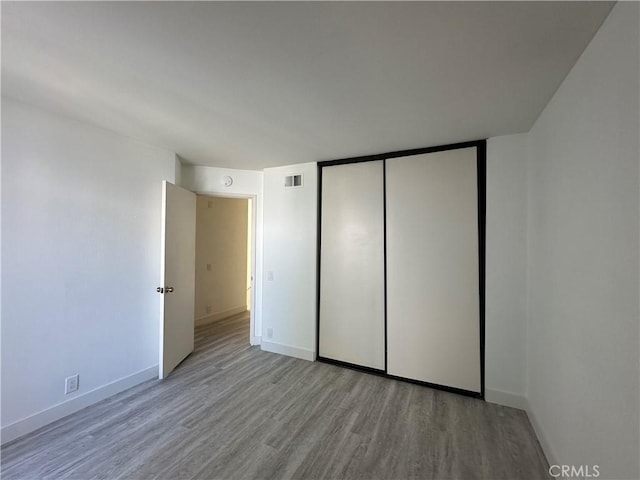 unfurnished bedroom with light hardwood / wood-style floors and a closet