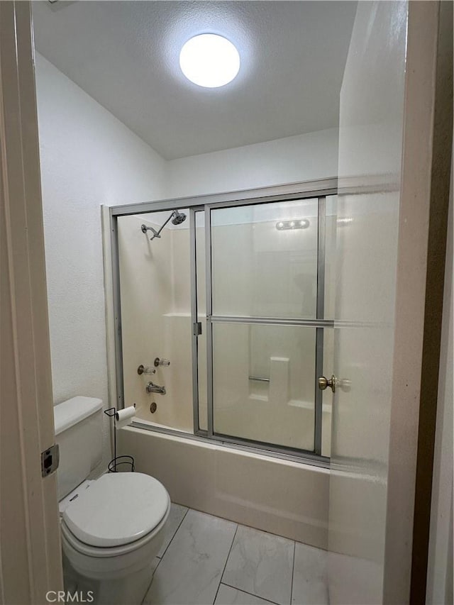 bathroom with a textured ceiling, combined bath / shower with glass door, and toilet