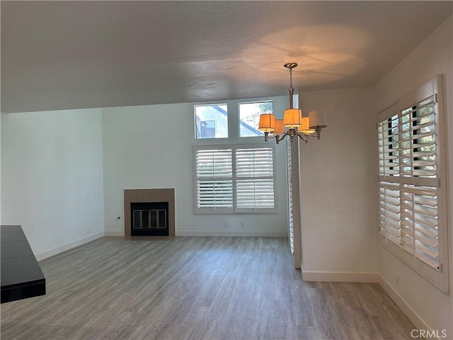 unfurnished living room featuring a textured ceiling, an inviting chandelier, and hardwood / wood-style floors