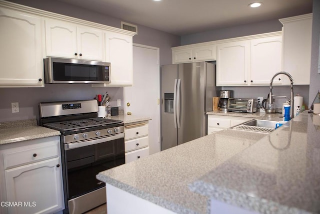 kitchen with appliances with stainless steel finishes, white cabinets, and sink