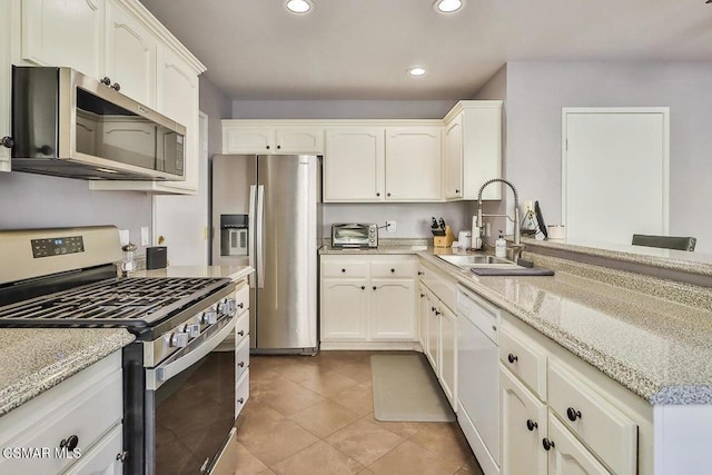 kitchen featuring sink, stainless steel appliances, white cabinets, and light stone countertops