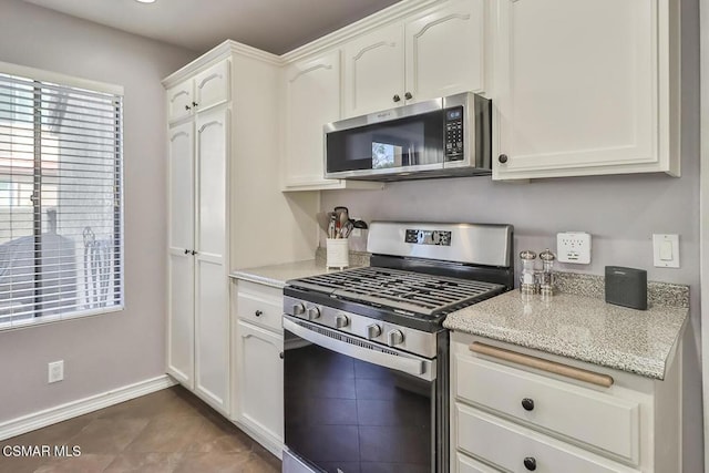 kitchen featuring white cabinetry, dark tile patterned flooring, and stainless steel appliances