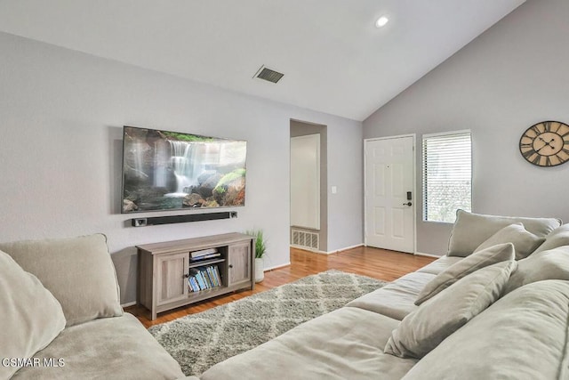 living room with high vaulted ceiling and light hardwood / wood-style floors