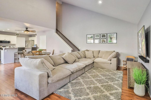 living room with ceiling fan, high vaulted ceiling, and light wood-type flooring