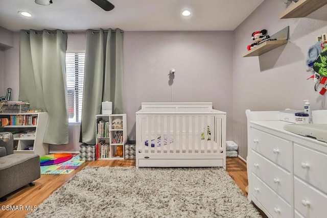 bedroom with a nursery area, sink, and light hardwood / wood-style flooring