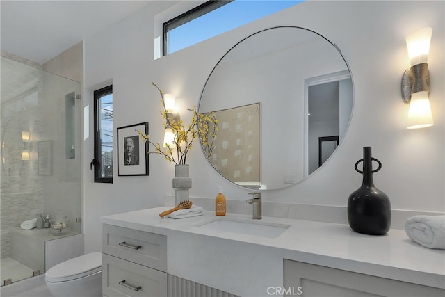 bathroom with tiled shower, vanity, and toilet