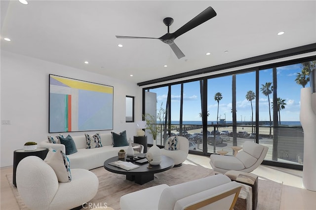 living room featuring a water view, ceiling fan, and floor to ceiling windows