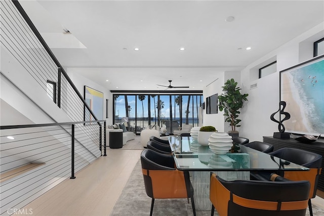 dining room featuring ceiling fan, a wall of windows, and light hardwood / wood-style flooring