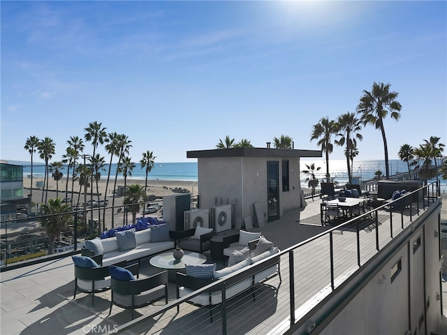 view of patio / terrace featuring a water view, a beach view, an outdoor hangout area, and washer / dryer