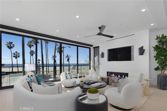 living room with light hardwood / wood-style flooring, a wall of windows, and ceiling fan