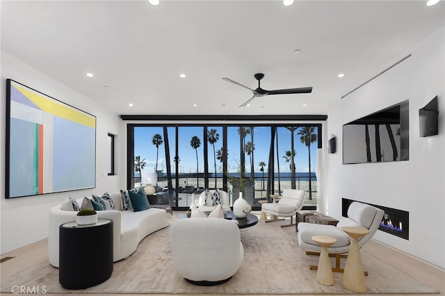 living room with floor to ceiling windows, plenty of natural light, ceiling fan, and light hardwood / wood-style flooring