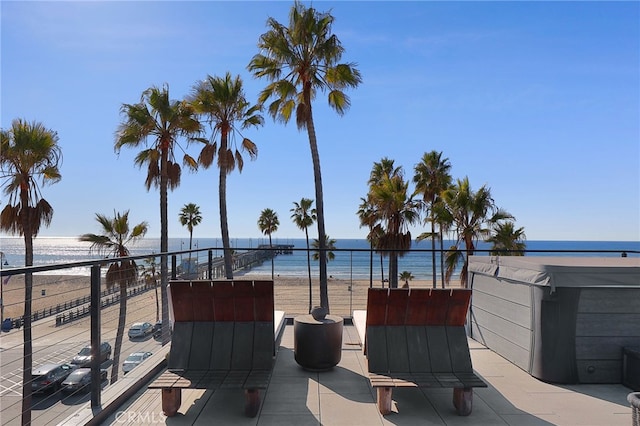 view of patio with a balcony, a water view, and a view of the beach