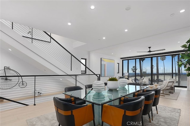 dining space featuring floor to ceiling windows, a water view, ceiling fan, and light hardwood / wood-style floors