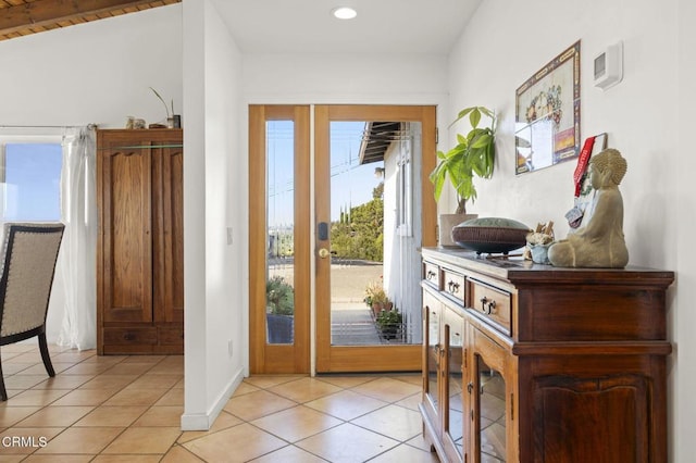 doorway with light tile patterned flooring and vaulted ceiling