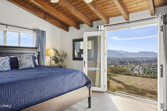 bedroom featuring a mountain view, vaulted ceiling with beams, wooden ceiling, and light hardwood / wood-style flooring