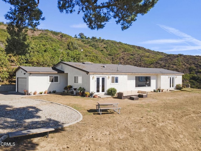 back of house with a garage, a mountain view, a yard, and an outdoor living space